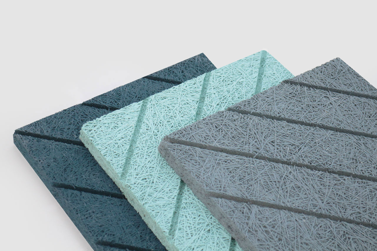 Three rectangular acoustic panels in dark blue, light blue, and gray, each with diagonal grooves and a textured, fibrous surface, are stacked slightly overlapping on a white background.