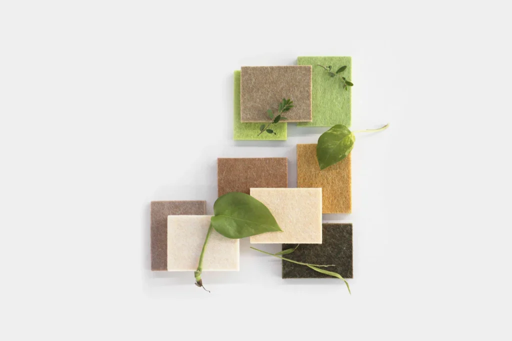 Eight square fabric swatches in earth tones and green shades are arranged in a grid on a light background, decorated with small green leaves and plant vines.