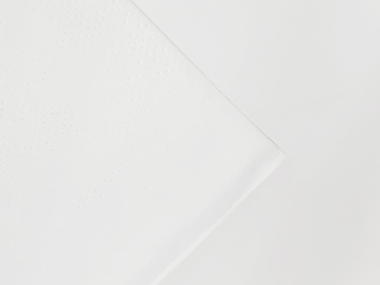 A close-up of a folded white paper napkin on a white background, with small dotted texture visible on part of the napkin.