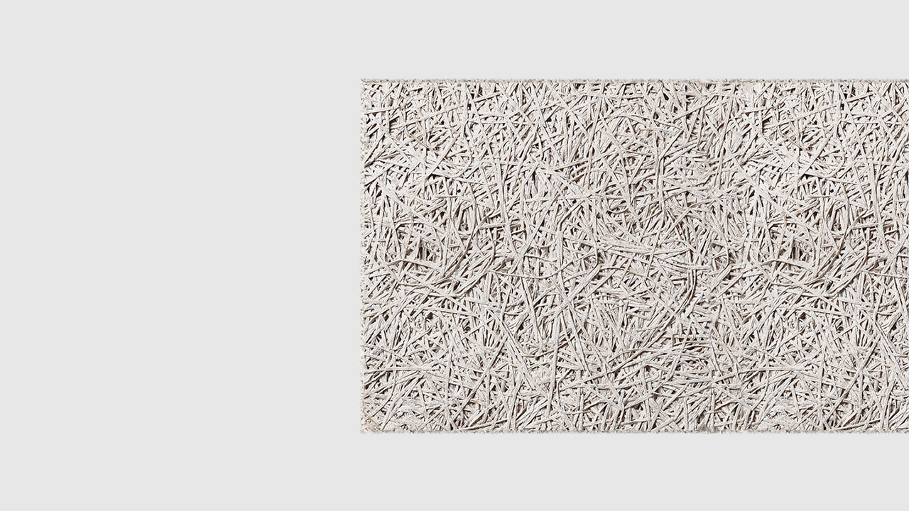 A close-up view of a textured, light grey rectangular panel made of compressed wood fibers on a plain white background.