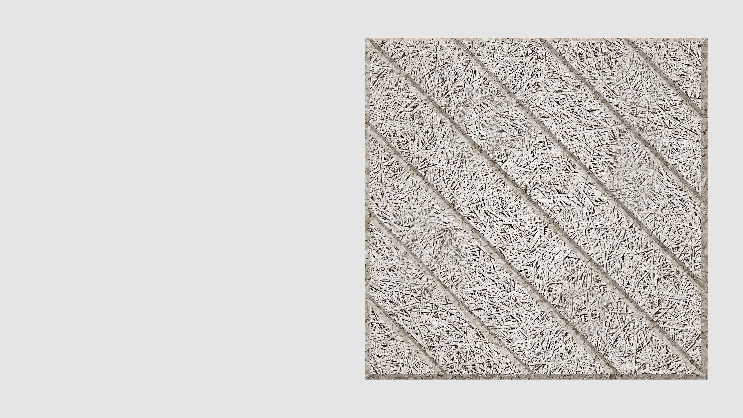 A close-up view of a square, textured panel featuring diagonal, grooved lines and a rough, straw-like surface pattern on a light gray background.