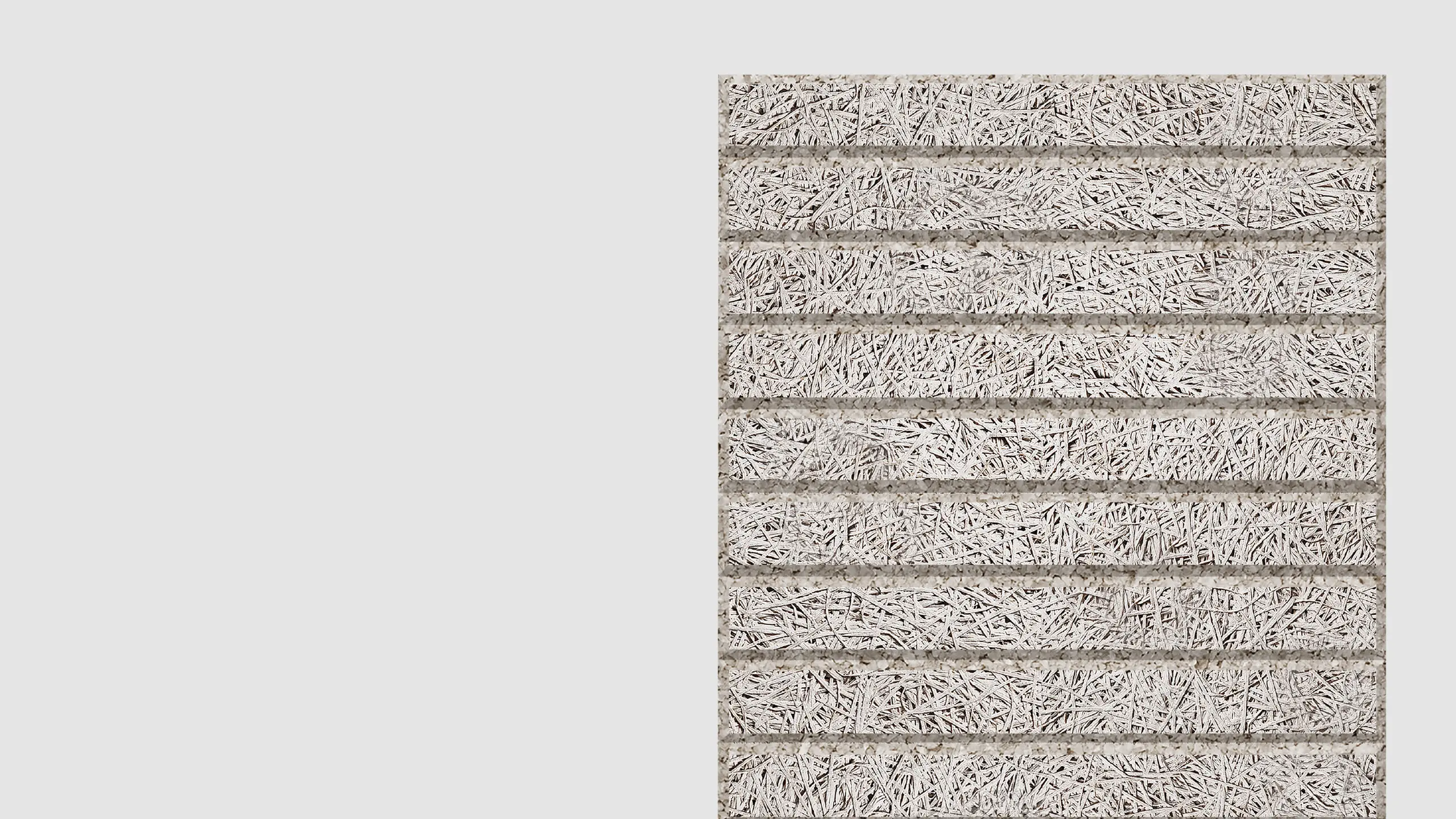 Close-up view of a textured, rectangular surface with horizontal rows made of interwoven, light-colored fibers, resembling a natural or synthetic mat. The background is plain light gray.