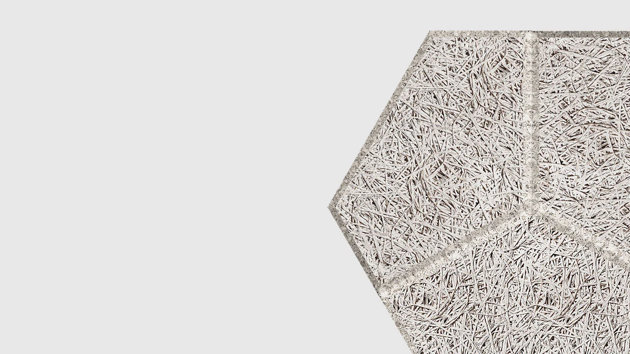 A close-up of a textured, light gray hexagonal panel made of intertwined wood fibers, positioned against a plain white background.