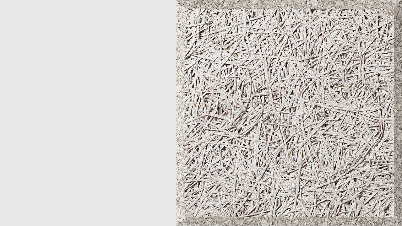A close-up of a textured, light gray panel made of compressed wood fibers, arranged in a random, crisscross pattern, with a rough, fibrous surface and defined rectangular edges.