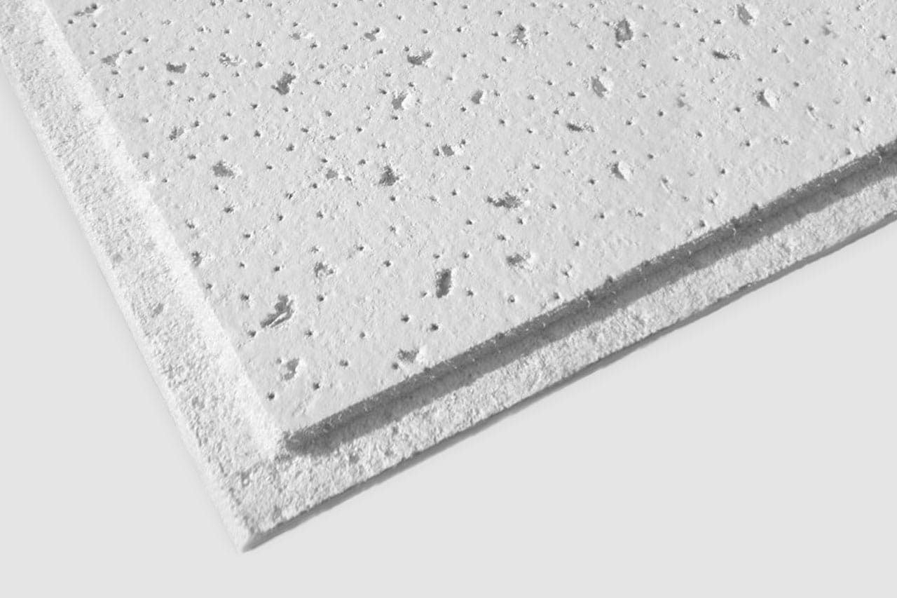 Close-up of the edge of a white acoustic ceiling tile with a textured, speckled surface and a beveled edge, isolated on a plain light background.