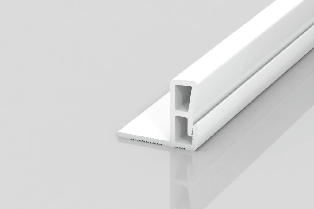 A white, rectangular plastic or metal strip with hollow sections and a notched base, placed on a reflective, light gray surface.