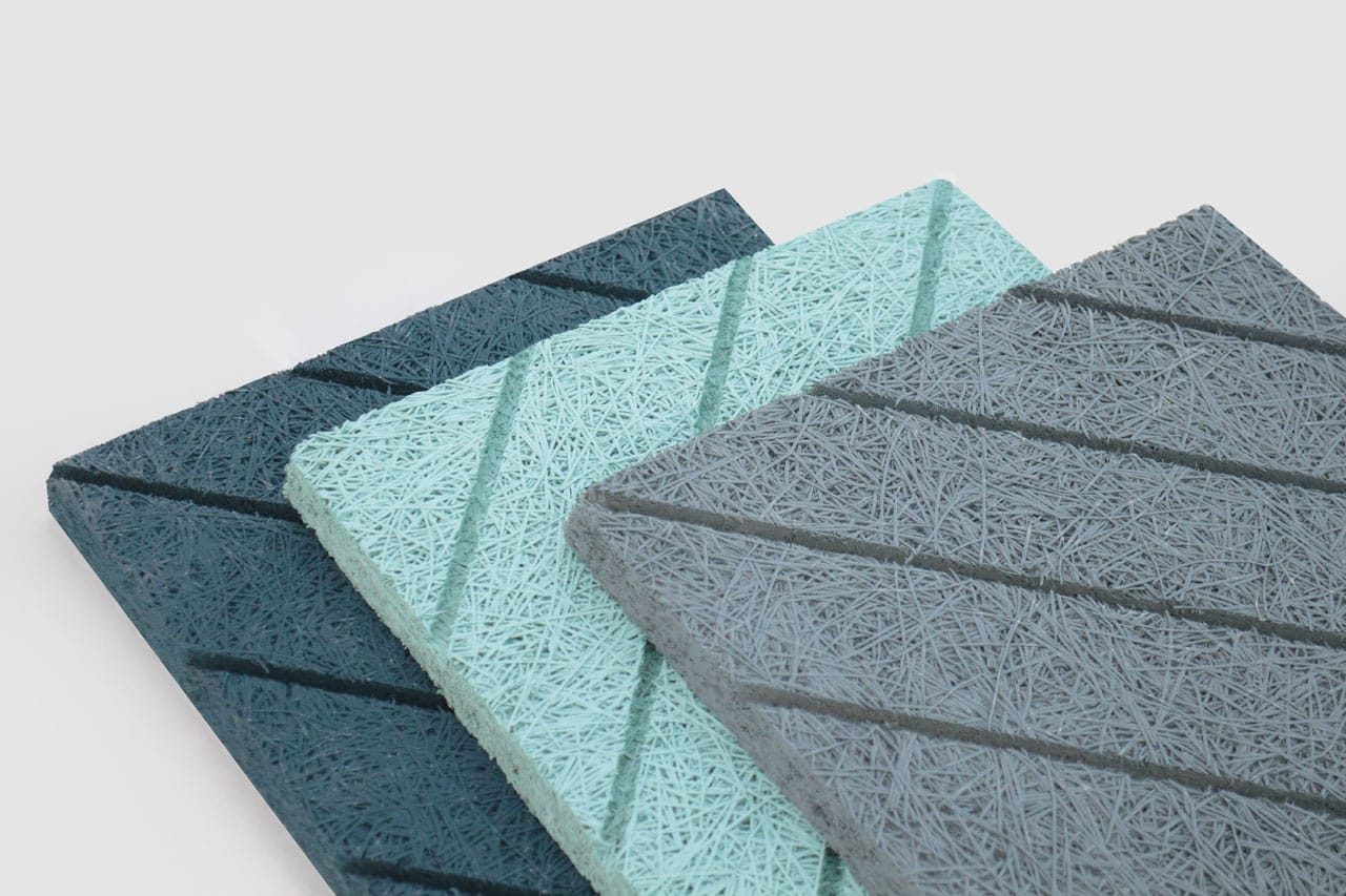 Three rectangular acoustic panels in dark blue, light blue, and gray, each with diagonal grooves and a textured, fibrous surface, are stacked slightly overlapping on a white background.