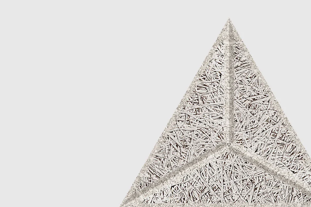 A close-up of a textured, triangular object with three compartments, made of interwoven, straw-like material, against a plain white background.