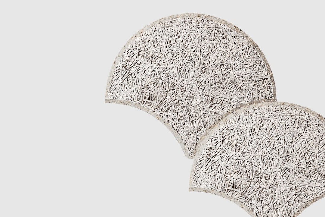 Two textured, semi-circular panels with a rough, fibrous surface overlap slightly on a plain, light background. The panels appear off-white and have an organic, woven appearance.
