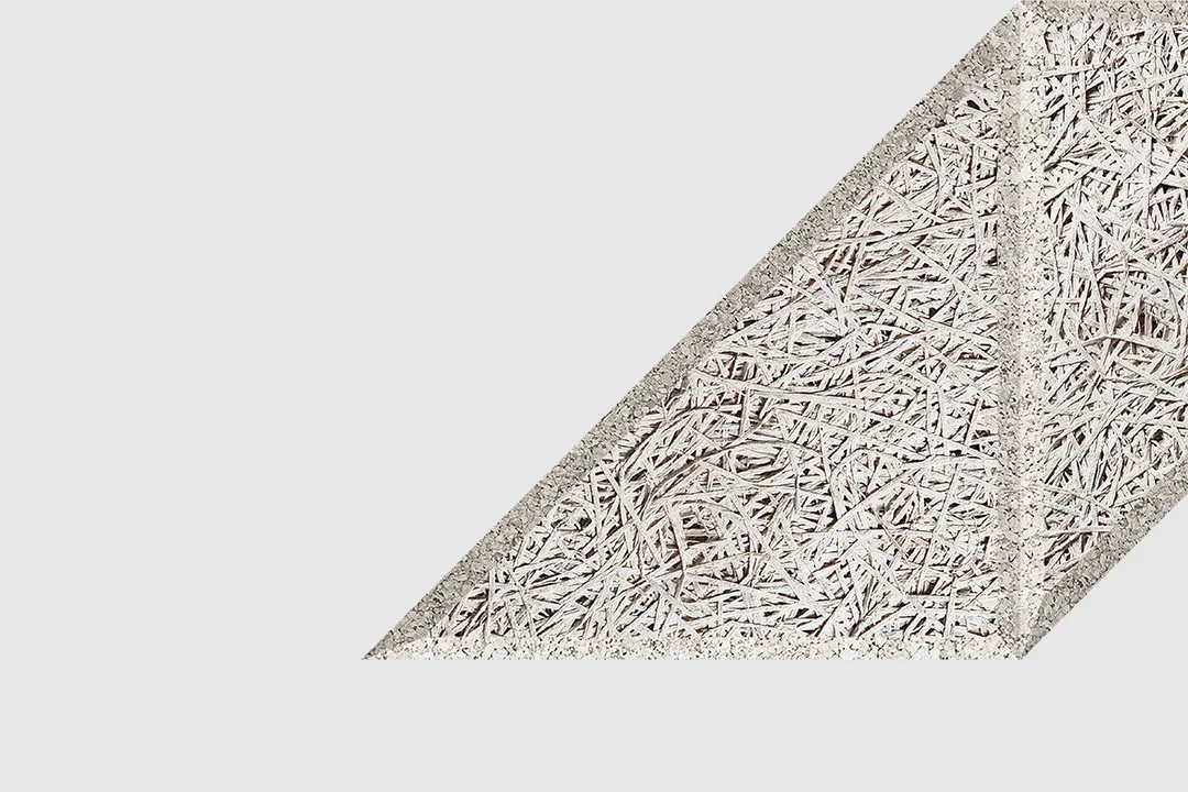 A textured, diagonal geometric shape with a rough, straw-like surface pattern on a plain white background. The shape is partially cropped on the right side.